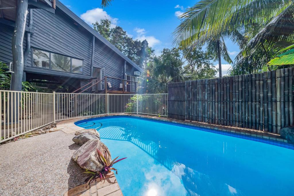 a swimming pool in front of a house with a fence at The Treehouse in Airlie Beach