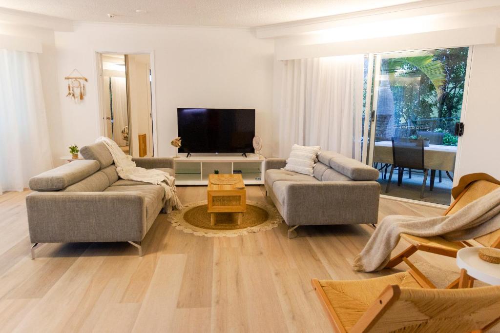 a living room with two couches and a flat screen tv at Coolum Sands Beachside Apartment in Coolum Beach