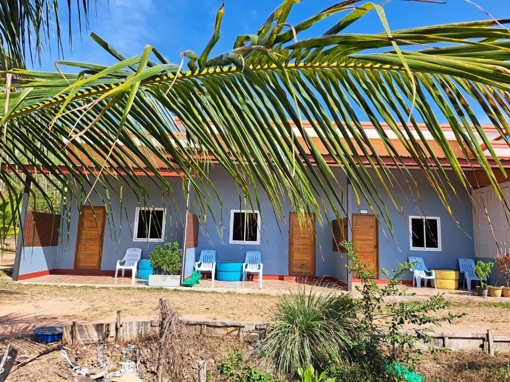 una casa azul con sillas y una palmera en Teacher House, en Phra Ae beach