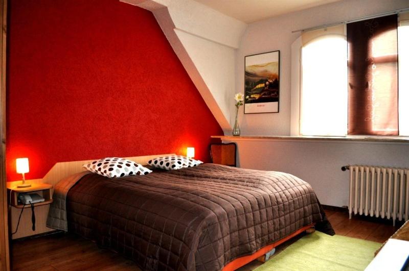 a bedroom with a large bed with a red wall at Hotel Restaurant Krone in Wolfach