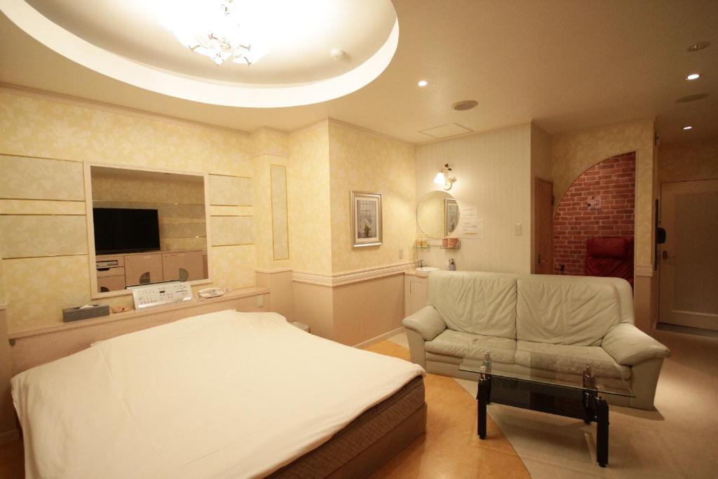 een slaapkamer met een bed, een bank en een stoel bij ホテルアンの家 in Ikaho
