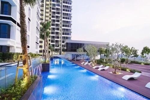 uma grande piscina com espreguiçadeiras e um edifício em Eco Nest 3 Bedroom Duplex Apartment em Nusajaya