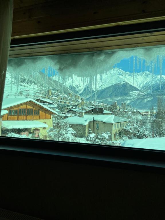 a view of a snow covered mountain from a window at Hotel Elite House in Mestia