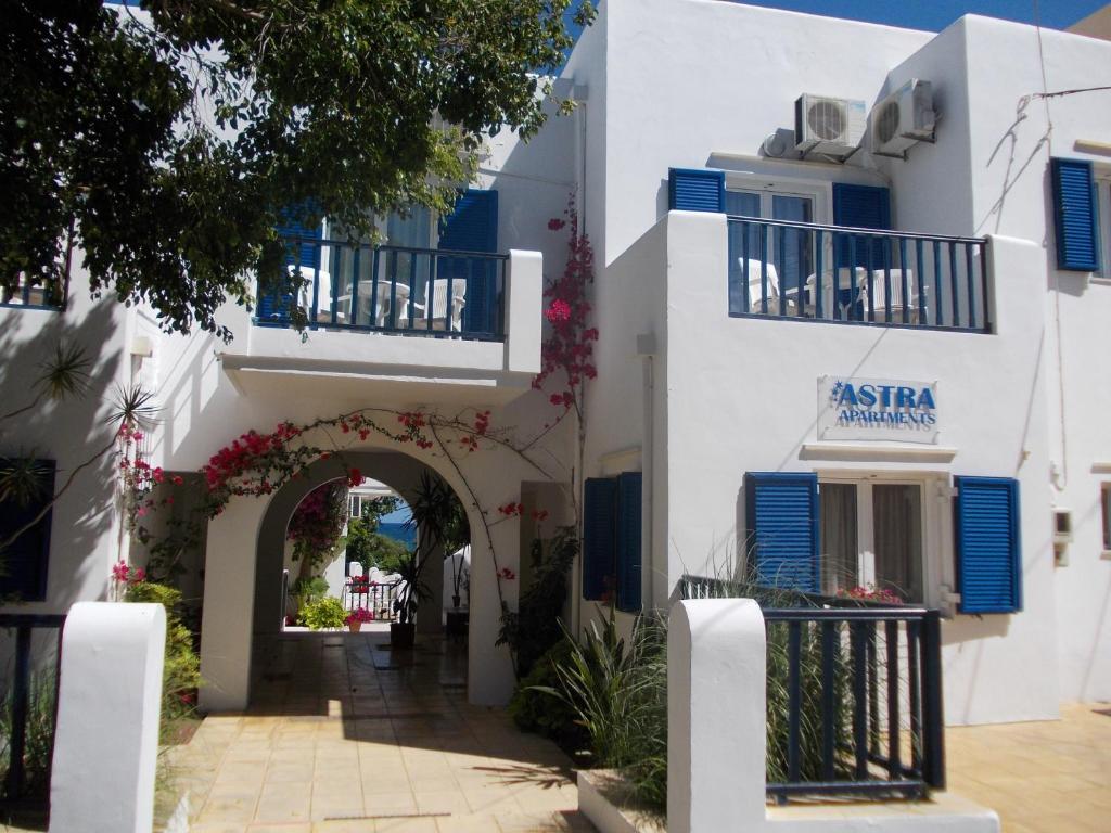 a white building with an archway and blue shutters at Astra Hotel Apartments in Kato Daratso