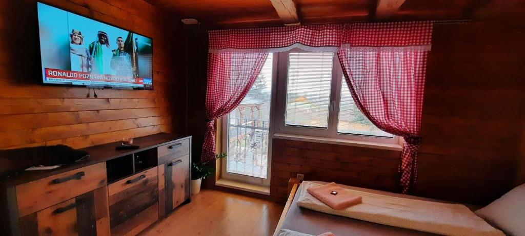 a living room with a flat screen tv and two windows at Penzion Kera in Rossitz