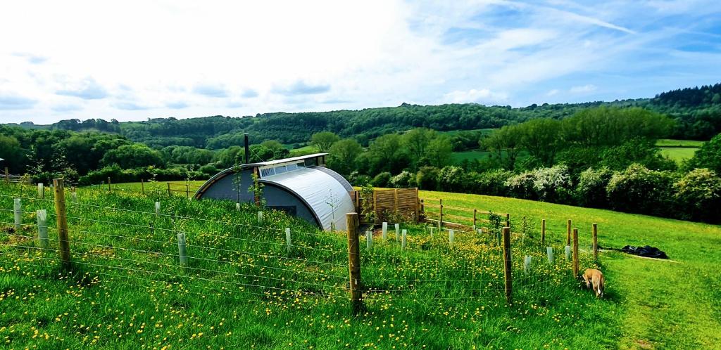 Una valla en un campo con una casa dentro en Huggeley Hall - Astounding, Chic, Valley Experience with Hot Tub, en Stanford on Teme