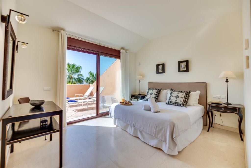 Habitación blanca con cama y balcón. en VACATION MARBELLA I Duplex con encanto bahía en Marbella