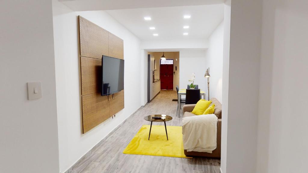 a living room with a couch and a tv on a wall at Central Valletta - 1 Bedroom maisonnette in Valletta