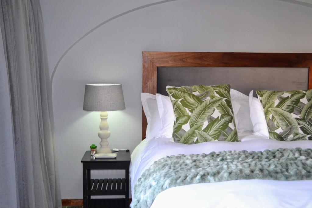 a bedroom with a bed and a lamp on a table at Cherry Grove 2 in Dullstroom