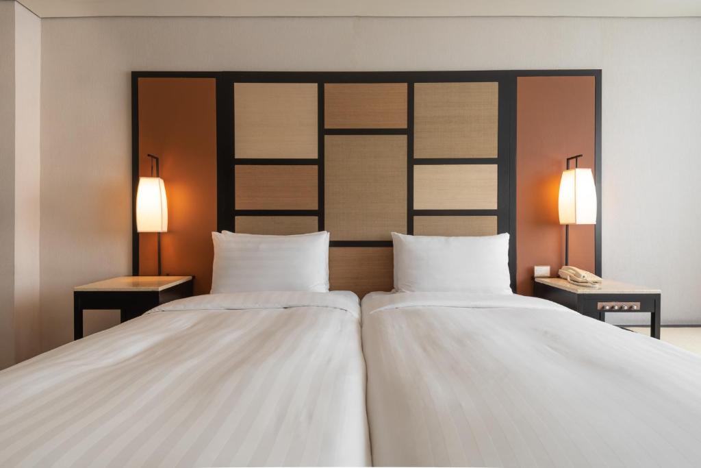 two white beds in a room with two lamps at Beitou Sweet Me Hot Spring Resort in Taipei