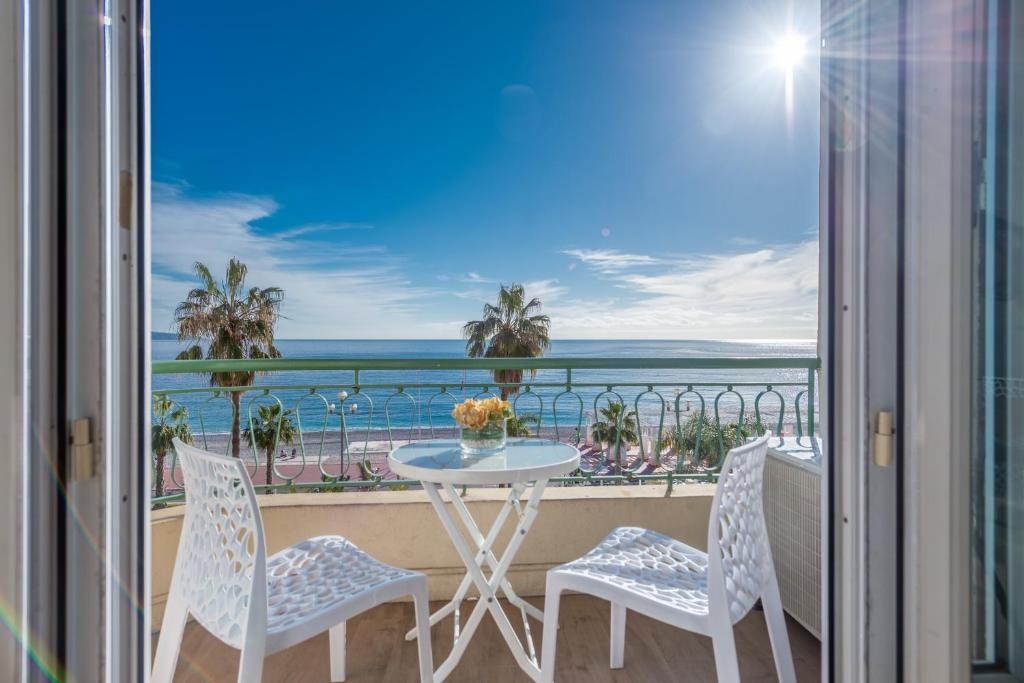 einen Balkon mit einem Tisch und Stühlen sowie Meerblick in der Unterkunft SEA FRONT - Panoramic view with Terraсe - 2BR in Nizza