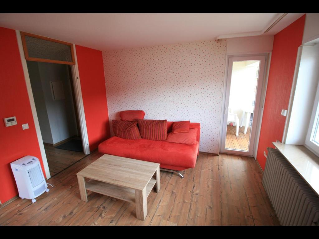 Sala de estar con sofá rojo y mesa de centro en NEU! Ferienwohnung im Herzen der Pfalz, en Kaiserslautern