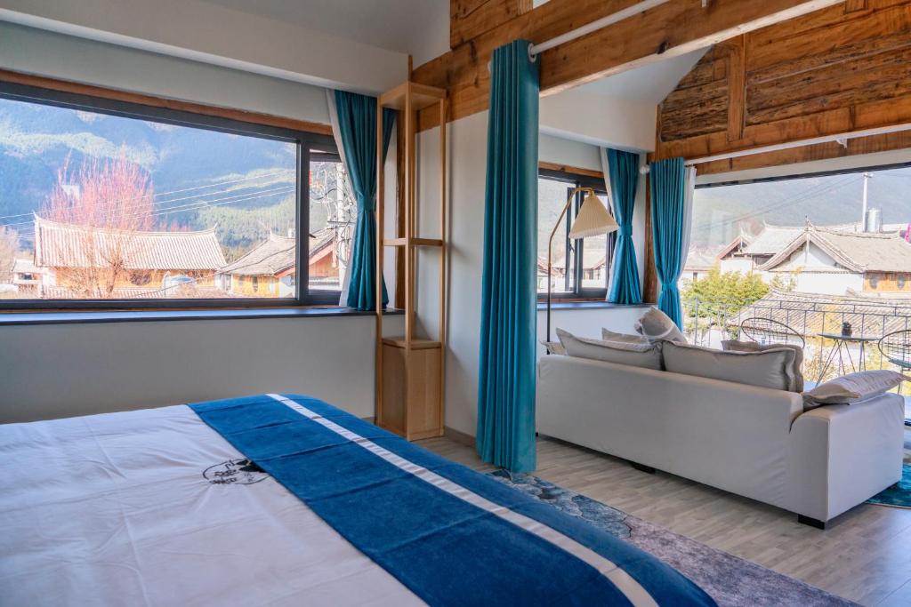 a bedroom with a bed and a couch and large windows at 玉龙白沙普宿客栈 in Lijiang