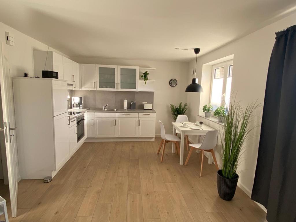 a kitchen with a table and a white refrigerator at NEU! Moderne Ferienwohnung Almdorf in Almdorf