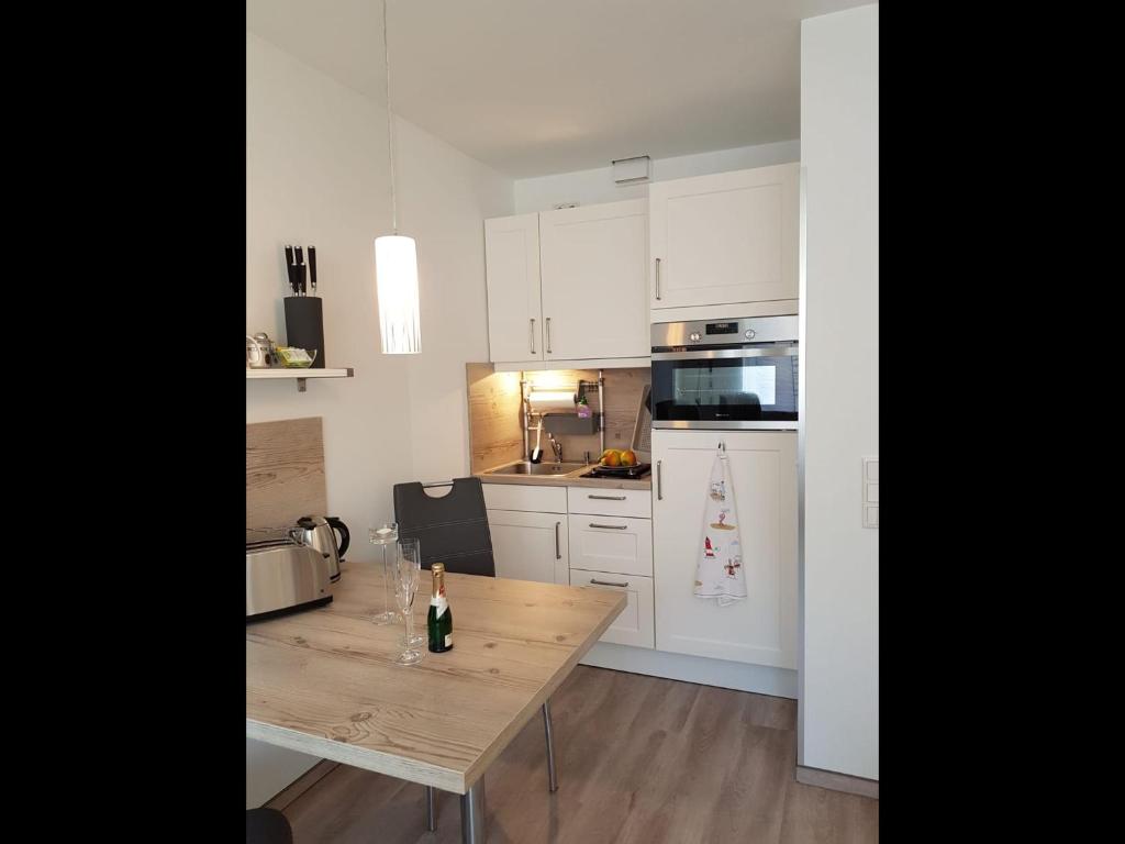 a kitchen with a wooden table with a bottle of wine at NEU! Ferienwohnung Mien lütte Boe SPO in Sankt Peter-Ording