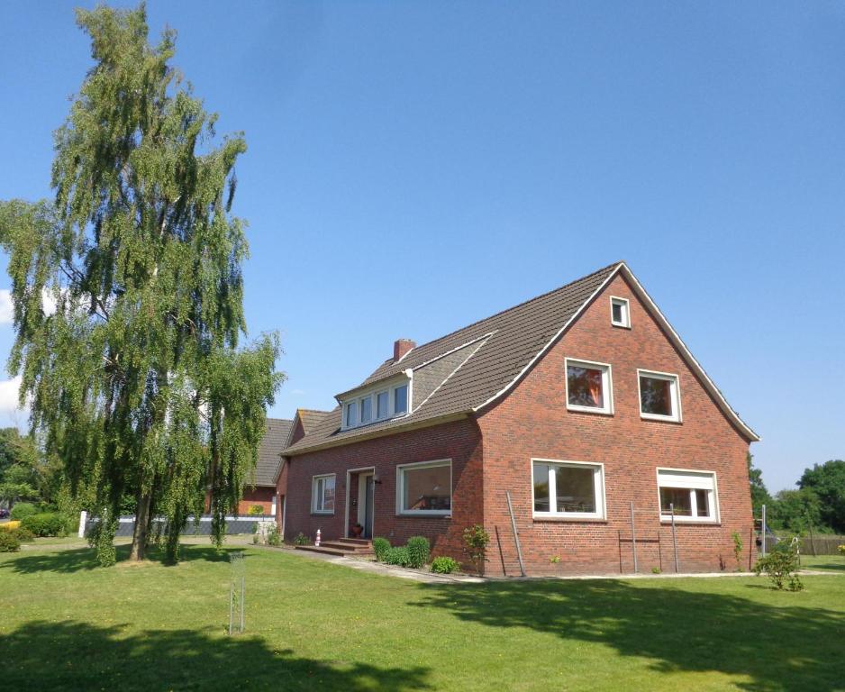 una gran casa de ladrillo con un árbol en el patio en NEU! Ferienwohnung im Leegmoor, en Aurich
