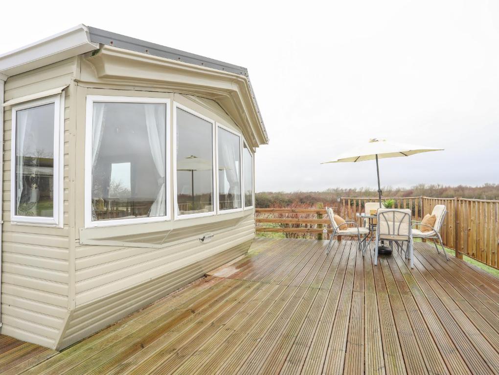 a house with a deck with a table and an umbrella at Mountain View Lodge in Holyhead