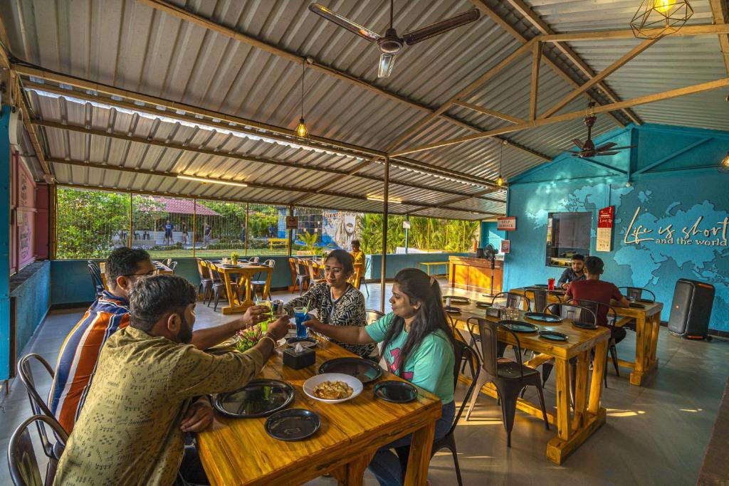 a group of people sitting at tables in a restaurant at Zostel Kolad in Kolād