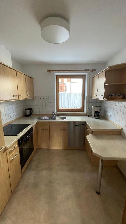 an empty kitchen with wooden cabinets and a window at Ferienwohnung Pauliner in Oberstdorf