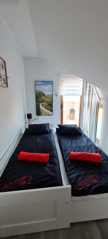 Una cama en una habitación con dos almohadas rojas. en IHB-Inter House of Balaton en Zamárdi