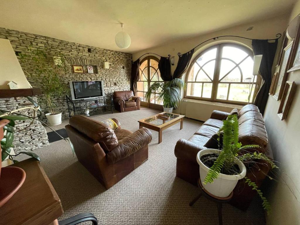 a living room with leather furniture and a large window at VillaPark Garden House in Szerencs