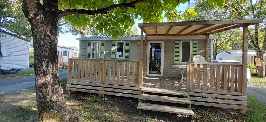 a tiny house with a porch next to a tree at Mobil home Saint Georges de Didonne in Saint-Georges-de-Didonne
