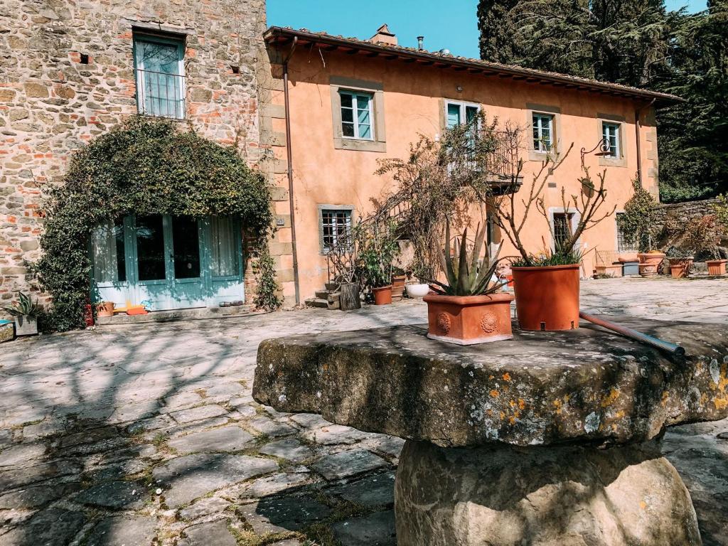 Un edificio con due piante in vaso, sedute su una roccia. di Casale gli ulivi a Donnini