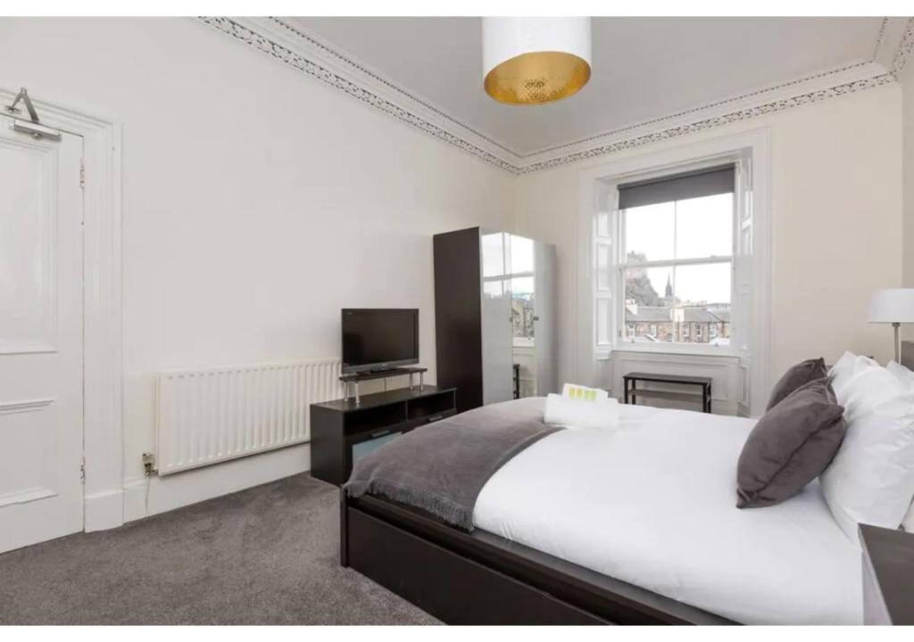 una camera bianca con letto e televisore di Spacious 3-bed Flat with Castle Views a Edimburgo