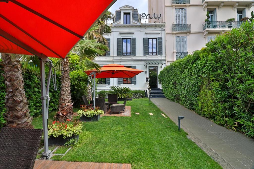 Villa Pruly Hotel Cannes Centre في كان: مظلة حمراء أمام المبنى