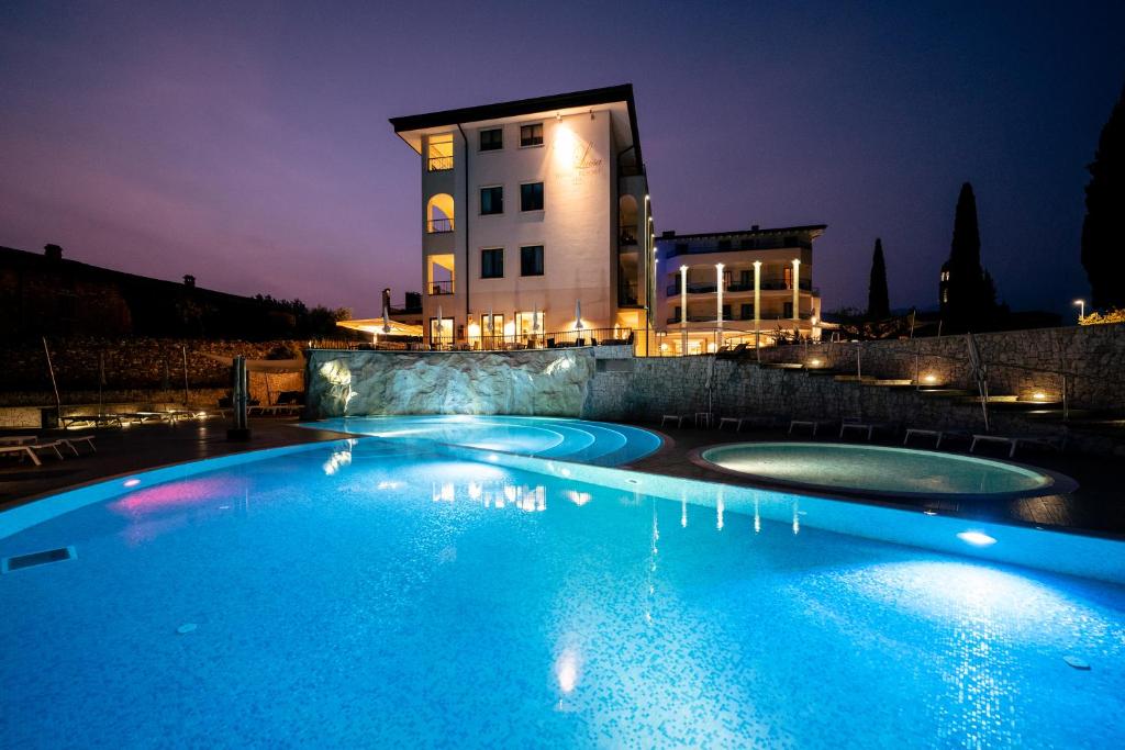 una piscina di fronte a un edificio di notte di Hotel Resort Villa Luisa & Spa a San Felice del Benaco