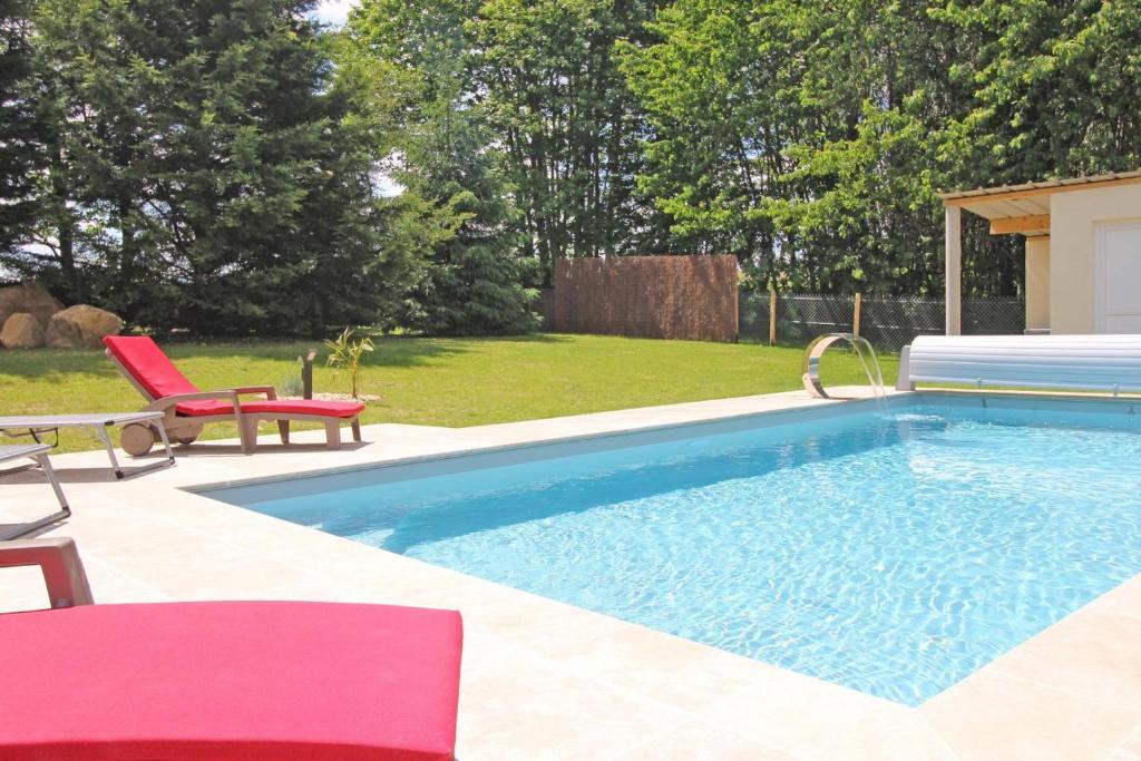 una piscina con una silla roja y una roja en Les cypres, en Magnac-Bourg