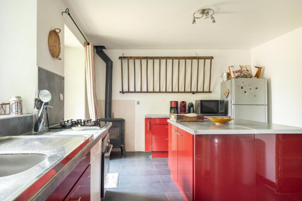 a kitchen with red cabinets and a white refrigerator at Maison Meslaie - Maison pour 8 avec piscine in Beaumont-en-Véron