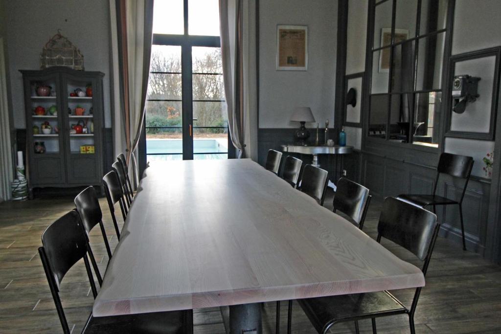 una mesa grande en una habitación con sillas alrededor en La gare aux oiseaux, en Cussac