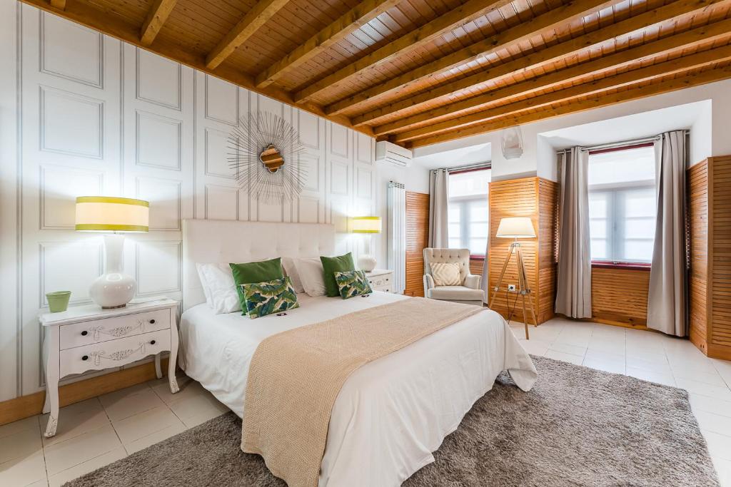 um quarto com uma grande cama branca com almofadas verdes em R3 Service - Five Senses in Coimbra em Coimbra