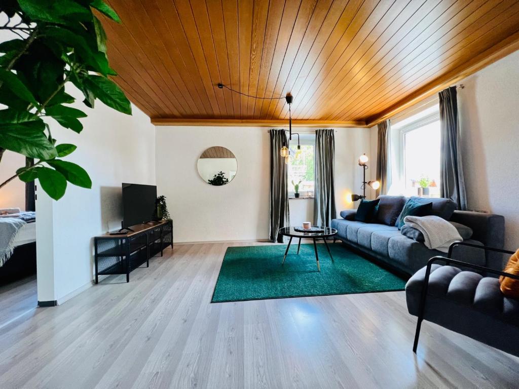 uma sala de estar com um sofá e um tecto de madeira em Ferienwohnung - ruhige Lage, Geräumig, mit Arbeits- und Parkplatz, Küche, Netflix, perfekt für Gruppen em Bad Staffelstein