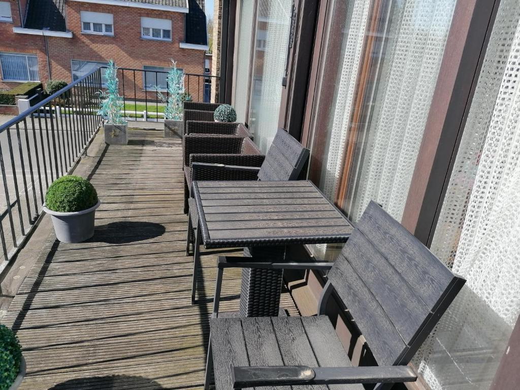 a wooden deck with benches and tables on a balcony at Logies Lily in Oudenburg