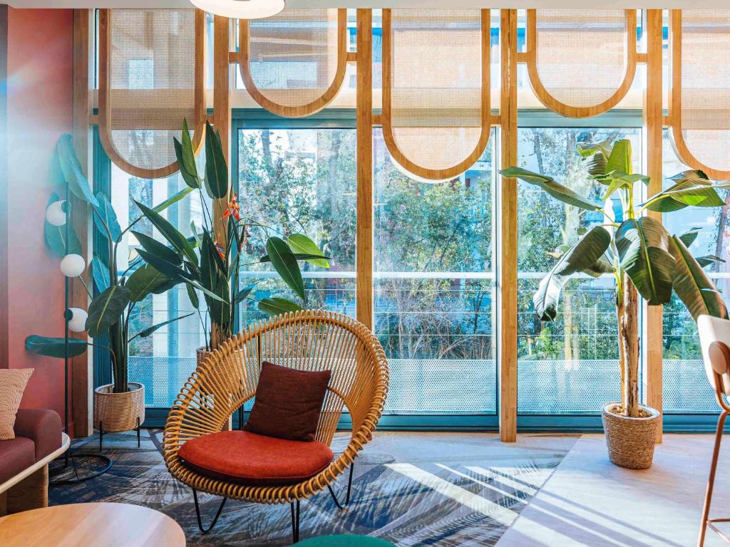 Pokój z rattanowym krzesłem i roślinami przed oknem w obiekcie ibis Styles Antibes w mieście Antibes