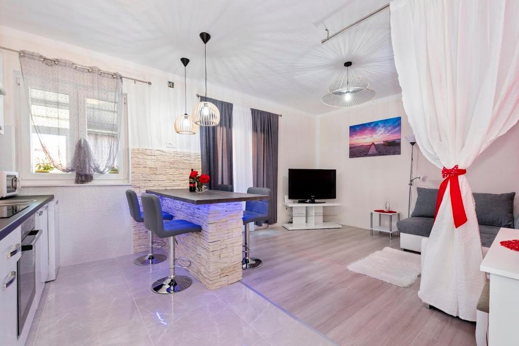 シベニクにあるLana Šibenikのテーブルと椅子のあるキッチンとリビングルーム