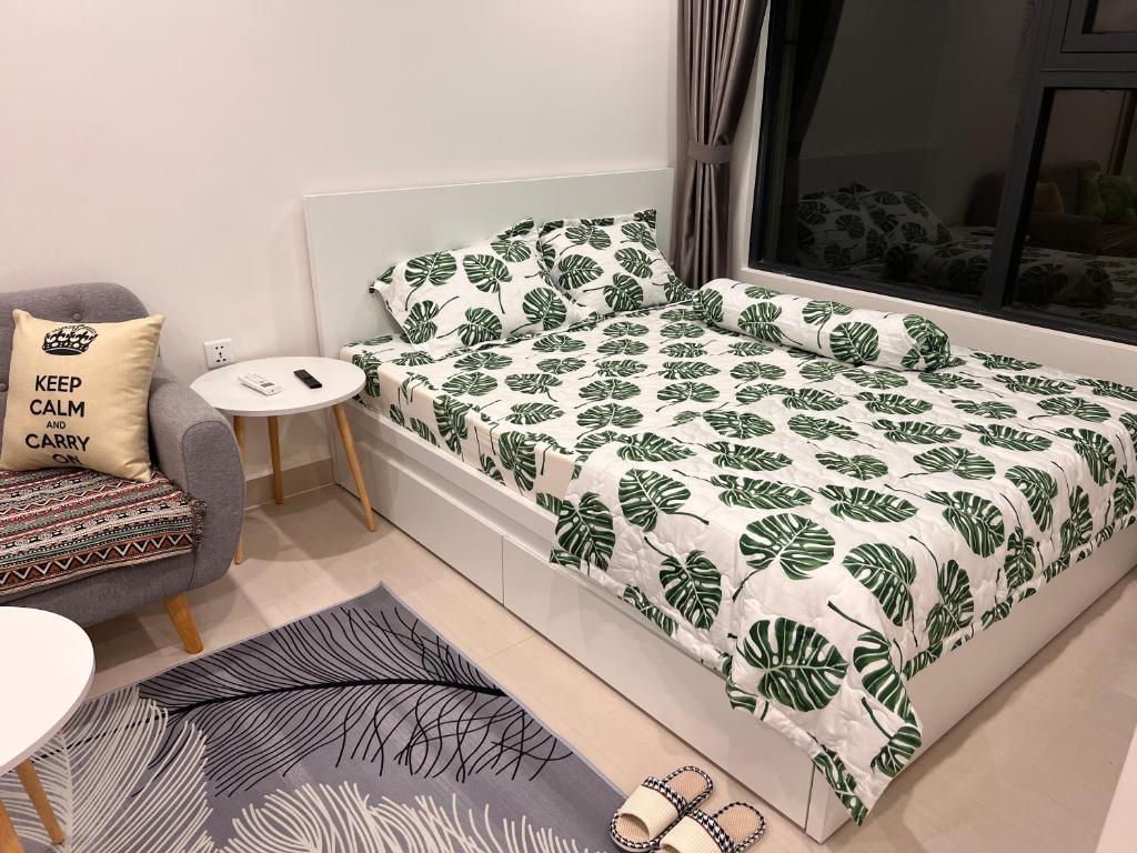 a bedroom with a bed with a green and white blanket at Vinhome Grand Park Homestay House in Gò Công