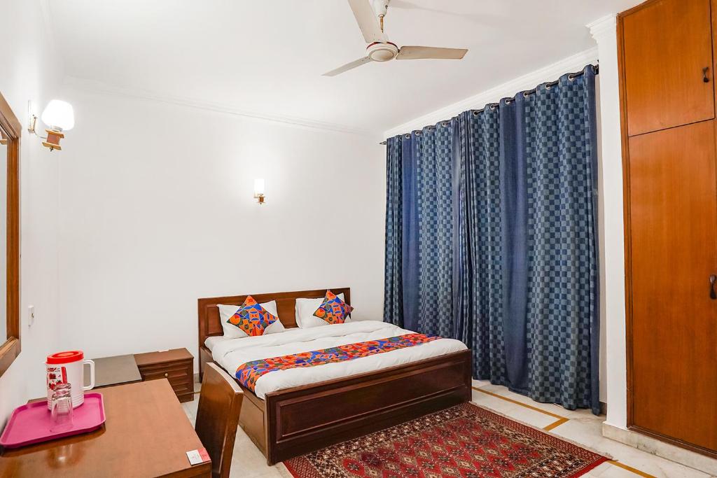 - une chambre avec un lit avec des rideaux bleus et une table dans l'établissement FabExpress Goodwill Homes, à New Delhi