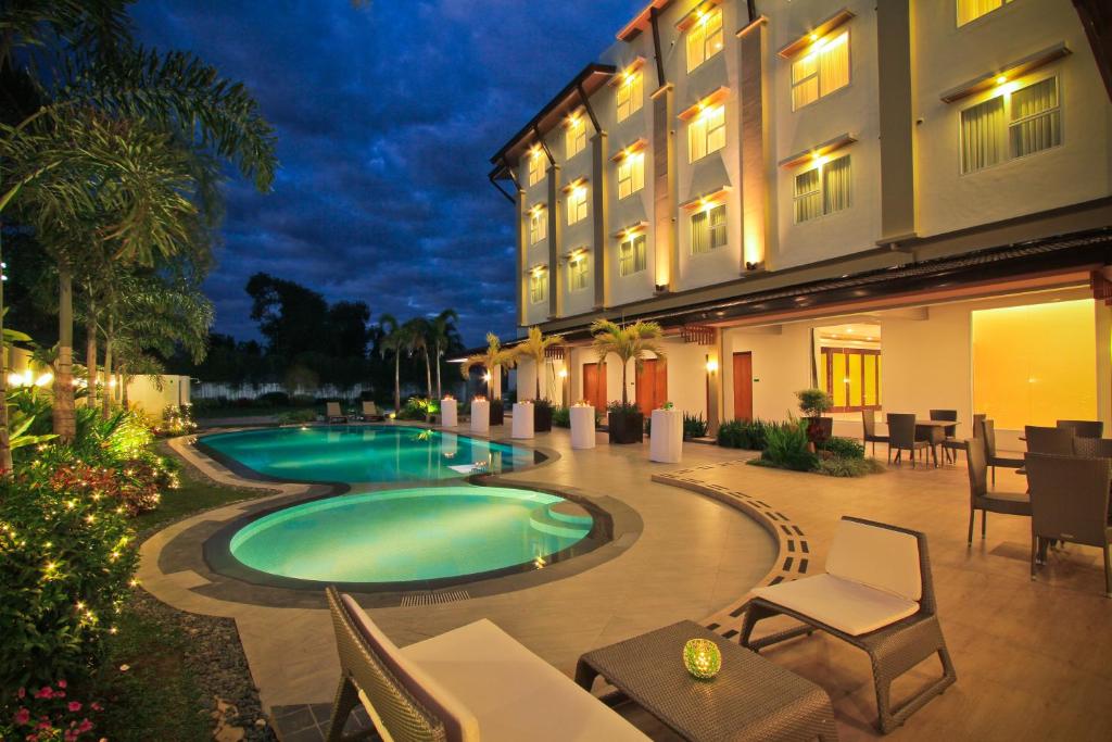 a hotel with a swimming pool in front of a building at The Harvest Hotel Managed by HII in Cabanatuan