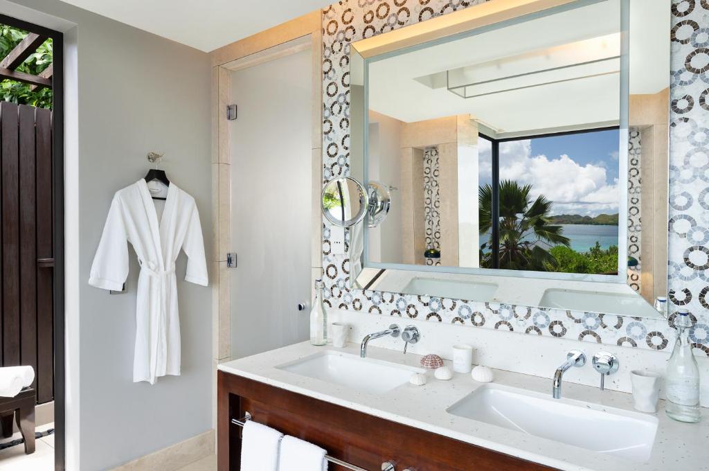 um banheiro com uma pia e um espelho em Raffles Seychelles em Baie Sainte Anne