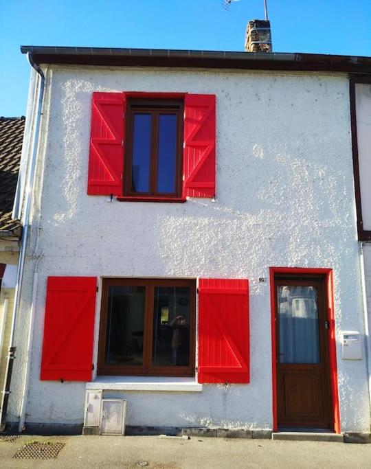 Un bâtiment blanc avec volets rouges dans l'établissement L'Embrun de la Baie de Somme, à Saint-Valery-sur-Somme