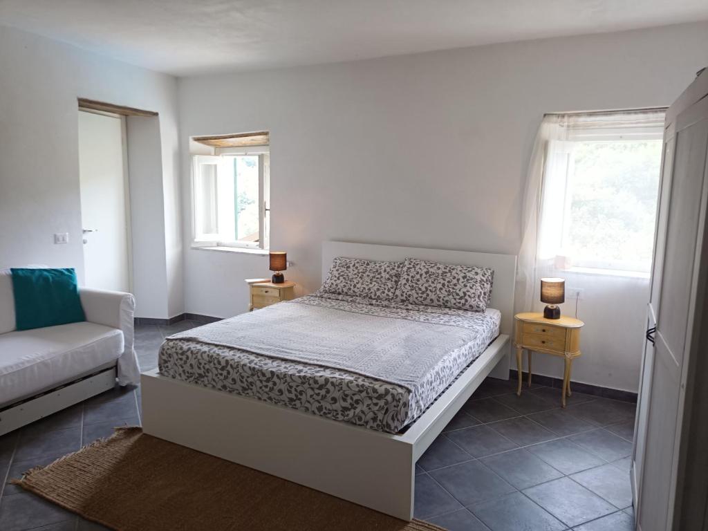 B&B Sant'Anna في كايرو مونتينوت: غرفة نوم بيضاء مع سرير وأريكة