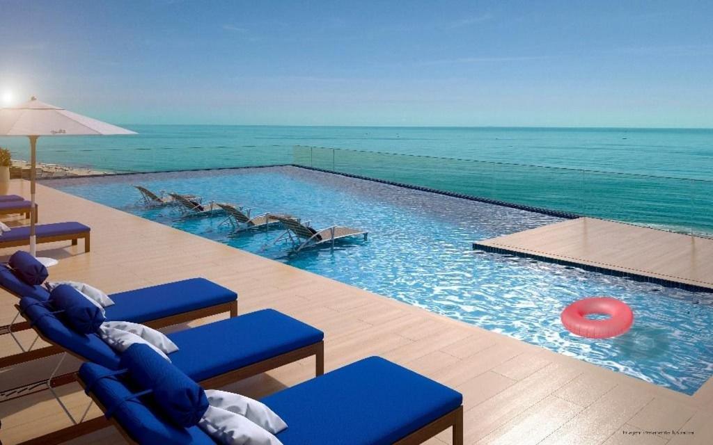 una piscina con sedie blu e frisbee rosso di Apartamento Venice Home Club Itacolomi Balneário Piçarras SC a Piçarras