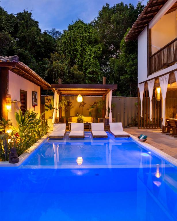 uma piscina com cadeiras e uma casa em Cottage Bahia em Arraial d'Ajuda