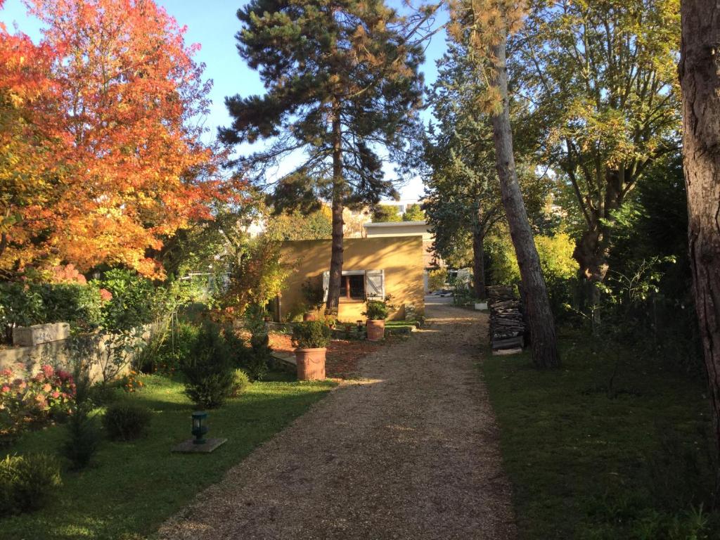 un sentiero che conduce a una casa con alberi autunnali di appartement fond de jardin 1 étage a Palaiseau