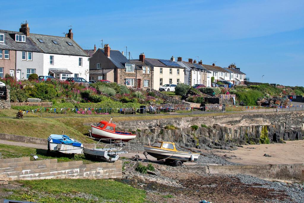 three boats sitting on the shore of a beach at Finest Retreats - Harbour House in Craster