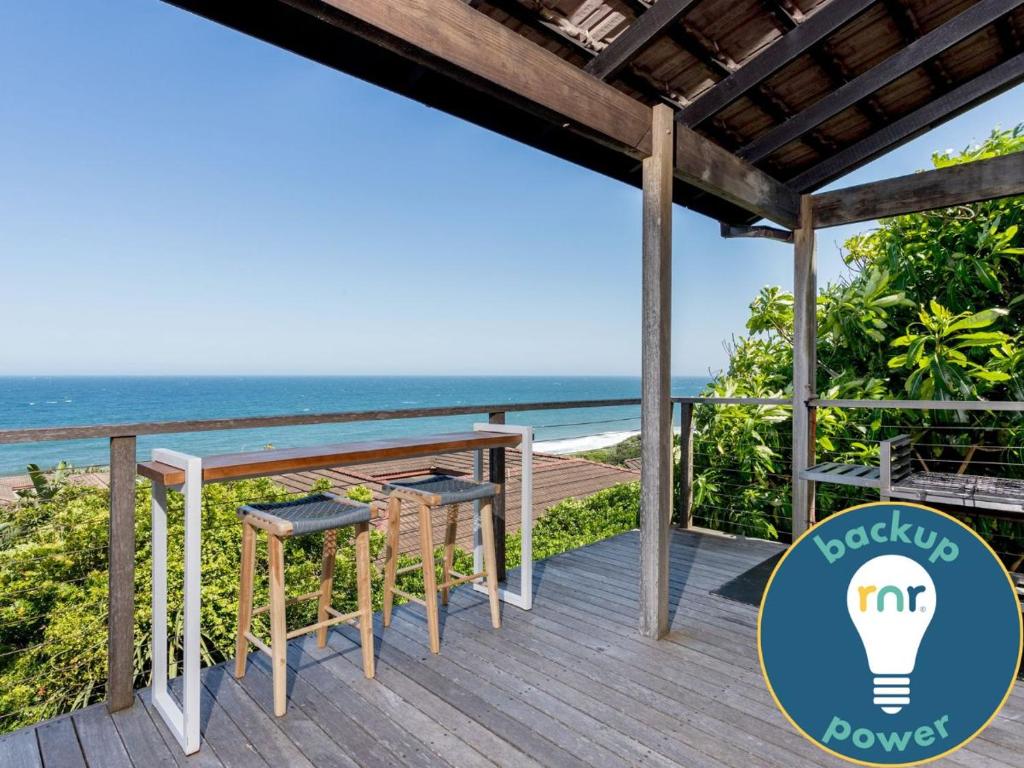 a deck with a table and chairs and the ocean at 8 Sovereign Sands Sea Views, Blythdale in KwaDukuza