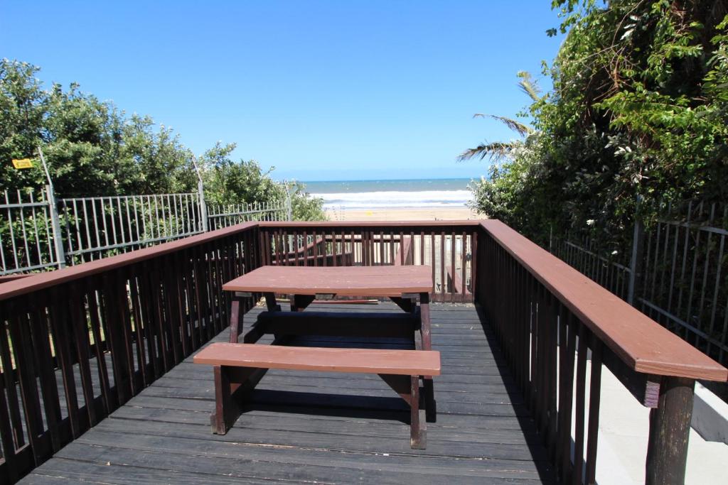 - une terrasse en bois avec une table et des bancs sur la plage dans l'établissement Santana 107, à Margate